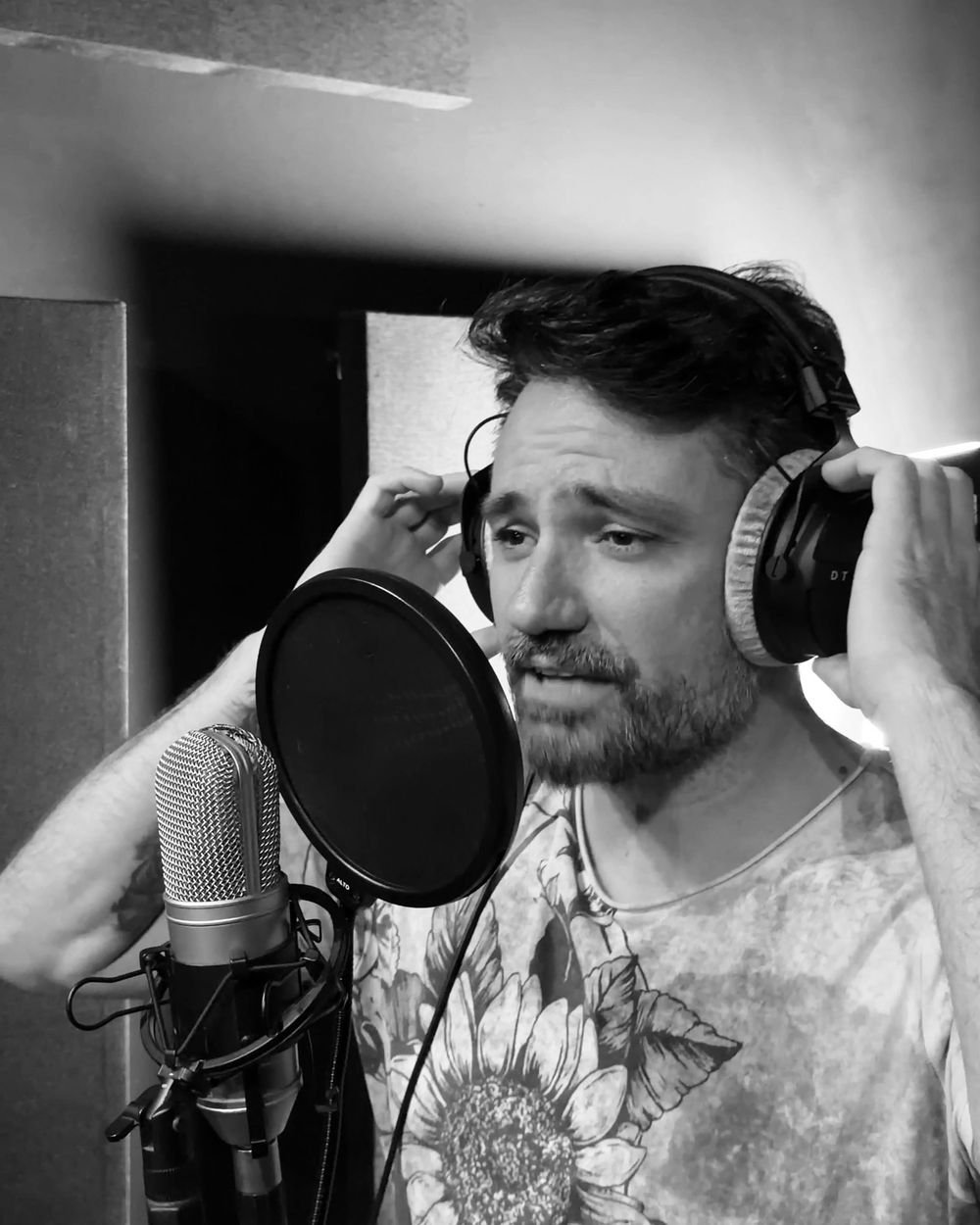 Vocalista da VELT gravando no estúdio, com fones e microfone, em preto e branco
